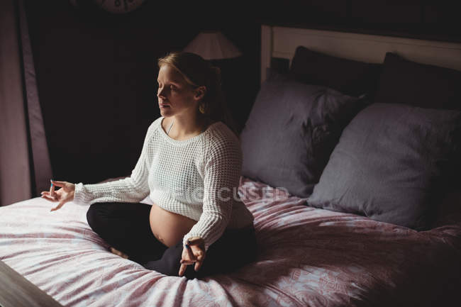 Pregnant woman performing yoga in bedroom at home — Stock Photo