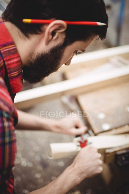 Homme utilisant un outil portatif pour lisser et niveler la surface d'une planche dans le chantier naval — Photo de stock