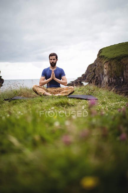 Hombre realizando yoga en acantilado - foto de stock