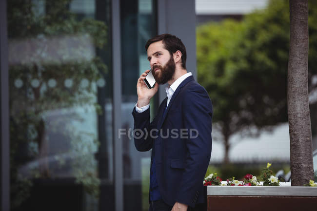 Businessman talking on mobile phone outside office — Stock Photo
