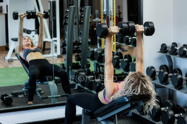Beautiful woman lifting dumbbells at gym — Stock Photo