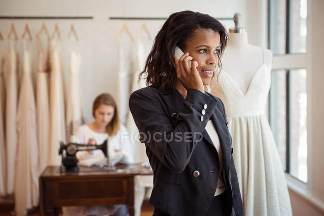 Modeschöpfer greift im Atelier zum Handy — Stockfoto