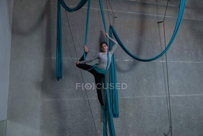 Gymnaste s'exerçant sur corde en tissu bleu dans un studio de fitness — Photo de stock