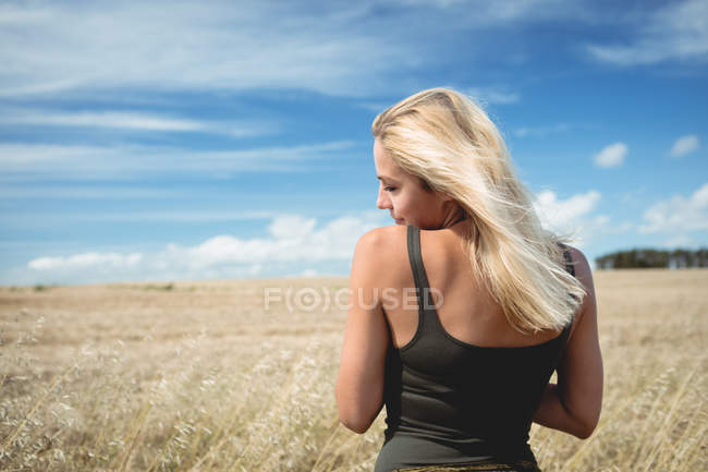 Rückansicht einer unbeschwerten blonden Frau, die im Feld steht — Stockfoto