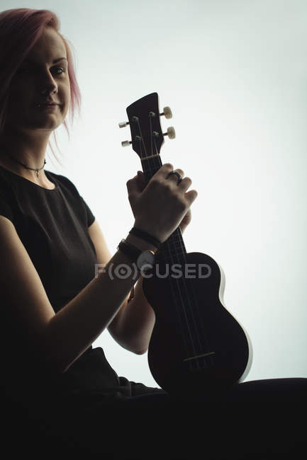 Portrait of woman sitting with a guitar in music school — Stock Photo