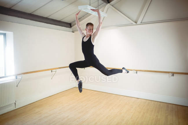 Молодой балерино прыгает во время репетиции балета в студии — стоковое фото