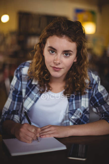 Portrait of beautiful mechanic writing in diary in workshop — Stock Photo
