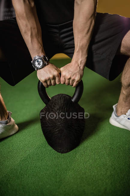 Cropped image of sportsman lifting weight in gym — Stock Photo