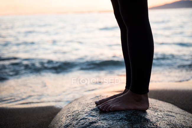 Bassa sezione di donna in piedi sulla roccia durante il tramonto — Foto stock