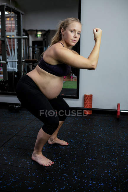 Portrait of pregnant woman performing exercise in gym — Stock Photo
