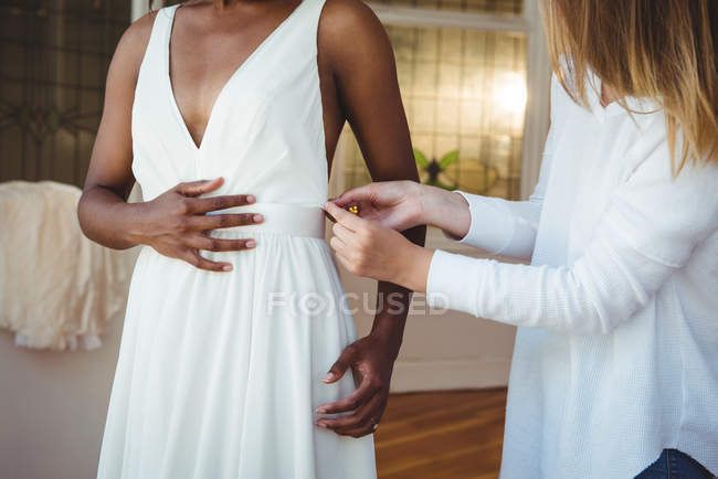 Женщина примеряет свадебное платье в студии при содействии модельера — стоковое фото