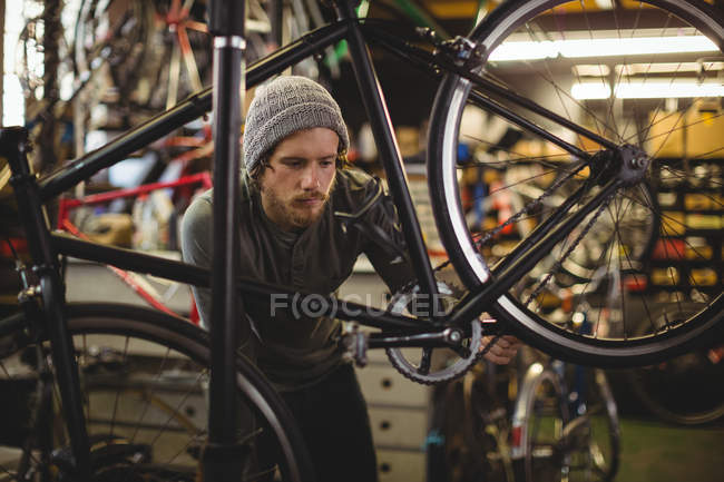 Mecânico examinando uma bicicleta na oficina de bicicleta — Fotografia de Stock