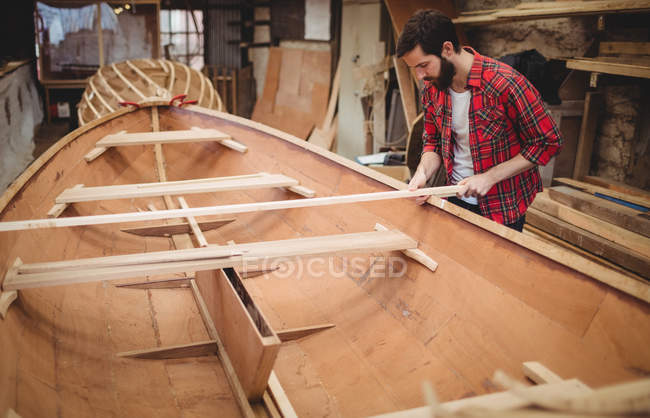 Homem preparando moldura de barco de madeira no estaleiro — Fotografia de Stock