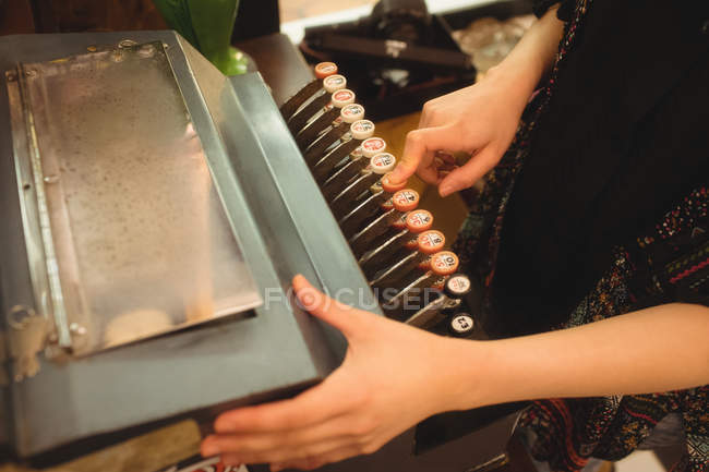 Mid section of woman using typewriter at counter in store — Stock Photo
