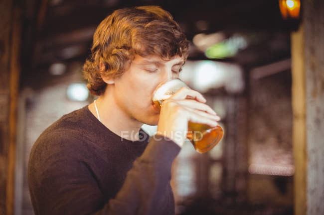 Un hombre tomando un vaso de cerveza en el bar - foto de stock