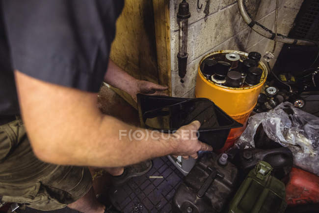 Mechaniker gießt in Werkstatt Öl in Kanister — Stockfoto