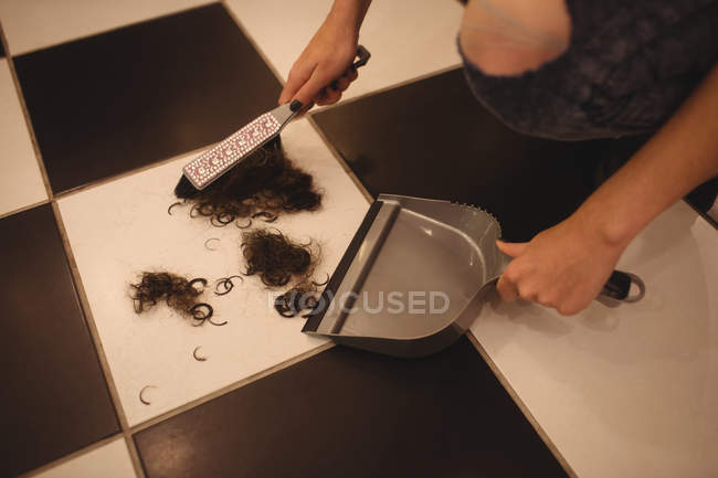 Hände von Mitarbeiterinnen mit der Kehrschaufel, um Haarabfälle im Salon zu reinigen — Stockfoto