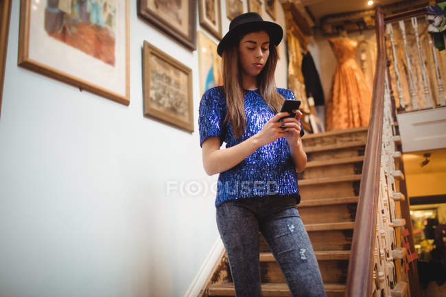 Жіночий персонал, що використовує мобільний телефон на сходах у магазині — стокове фото