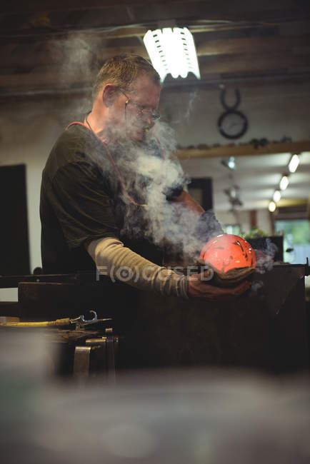 Glasbläser formen mundgeblasenes Glasstück mit feuchtem Tuch in Glasbläserei — Stockfoto