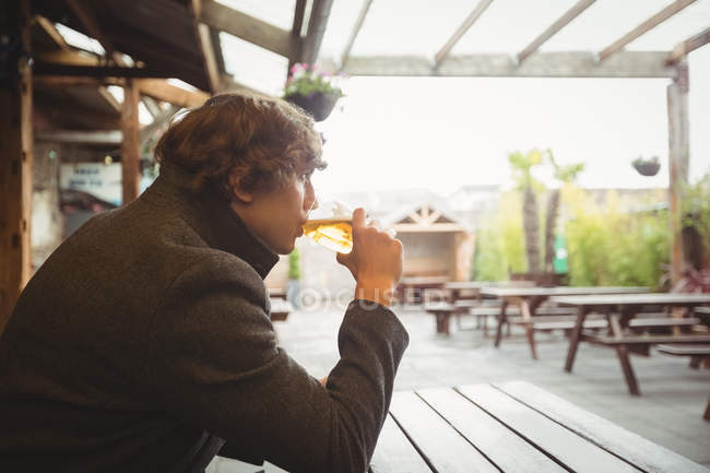 Un hombre pensativo tomando un vaso de cerveza en el bar - foto de stock