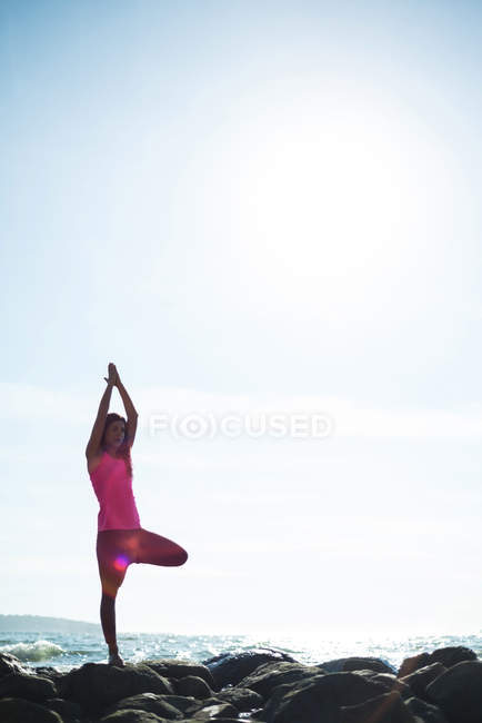 Mulher bonita que executa ioga na rocha no dia ensolarado — Fotografia de Stock
