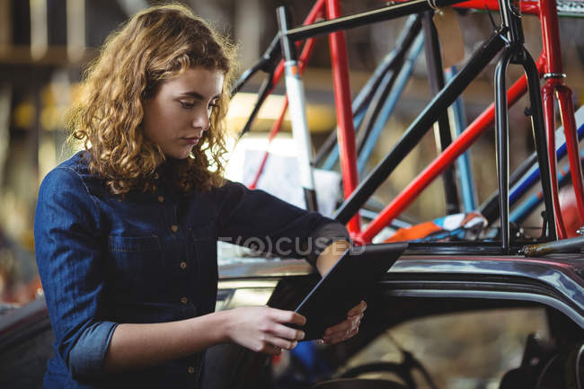 Механик с помощью цифрового планшета во время ремонта велосипеда в мастерской — стоковое фото