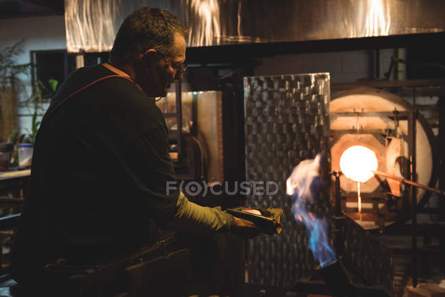Glassblower shaping blown glass piece with wet cloth at glassblowing factory — Stock Photo