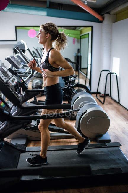 Hermosa mujer haciendo ejercicio en la cinta de correr en el gimnasio - foto de stock