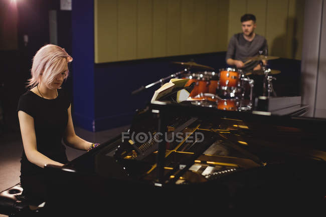 Female and male students playing piano and drum set in a studio — Stock Photo