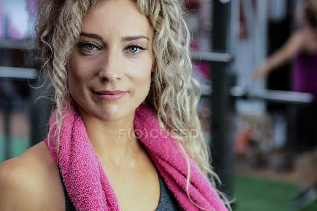 Porträt einer schönen Frau mit einem Handtuch um den Hals im Fitnessstudio — Stockfoto