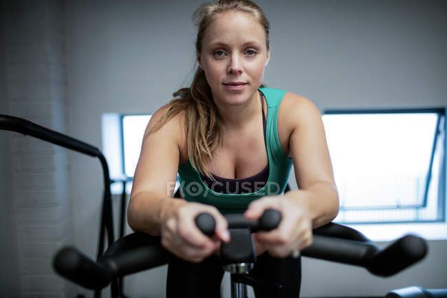 Portrait of pregnant woman working out on exercise bike at gym — Stock Photo