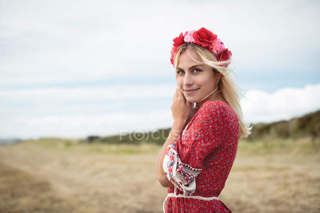 Веселая блондинка в цветочной тиаре, стоящая в поле — стоковое фото