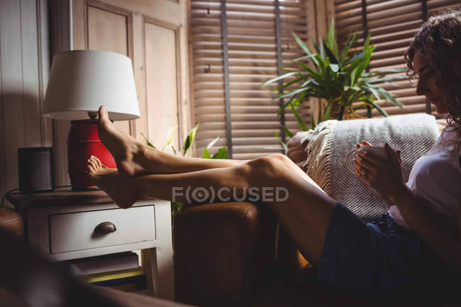Bella donna che prende il caffè in soggiorno a casa — Foto stock