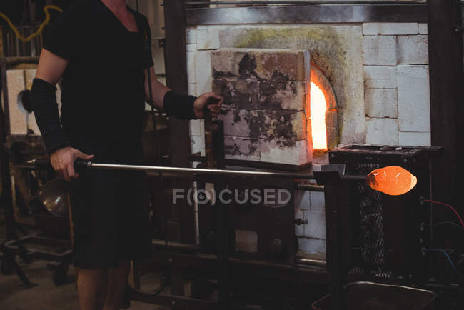 Cropped image of Glassblower heating glass in furnace at glassblowing factory — Stock Photo