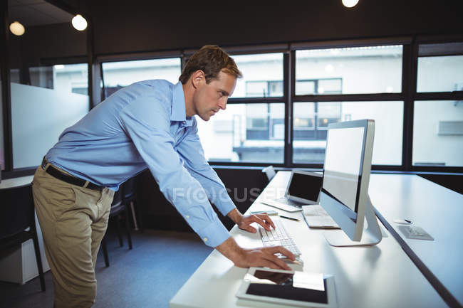 Businessman using desktop pc in office — Stock Photo
