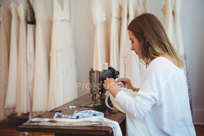 Costureira feminina costura na máquina de costura no estúdio — Fotografia de Stock