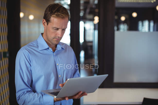 Homme d'affaires réfléchi en utilisant un ordinateur portable dans le bureau — Photo de stock