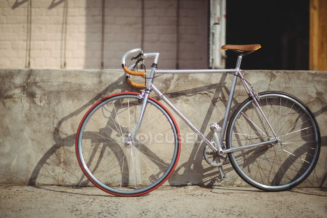 Vélo appuyé contre le mur le jour ensoleillé — Photo de stock