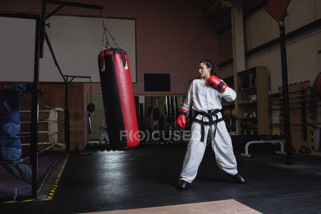 Woman practicing karate with punching bag in fitness studio — Stock Photo