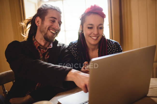 Sorrindo casal hipster usando laptop enquanto sentado à mesa — Fotografia de Stock