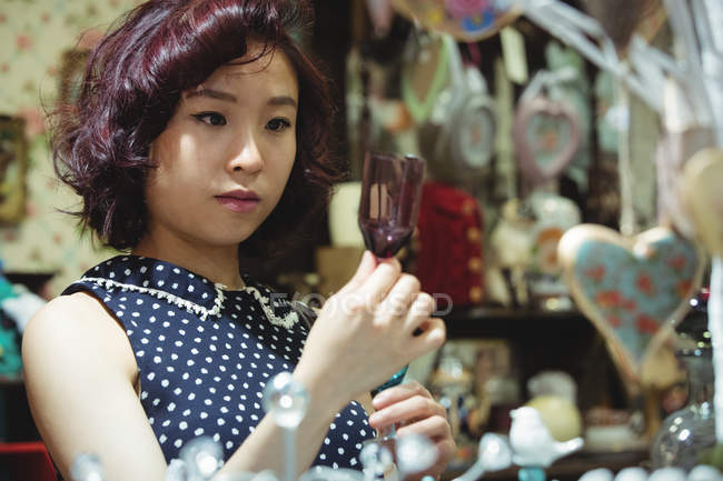 Femme élégante sélectionnant une tasse dans un magasin de bijoux d'antiquité — Photo de stock