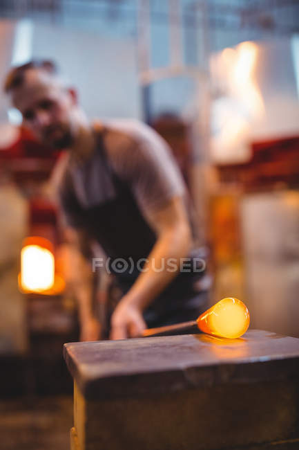 Стеклодув, формирующий расплавленное стекло на стекольном заводе — стоковое фото