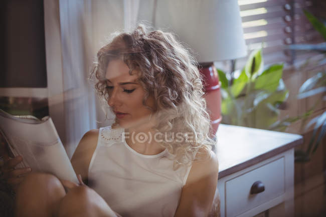 Красива жінка читання журналу у вітальні на дому — стокове фото