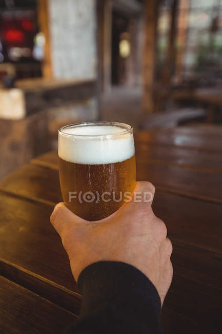 Hombre sosteniendo un vaso de cerveza en el bar - foto de stock