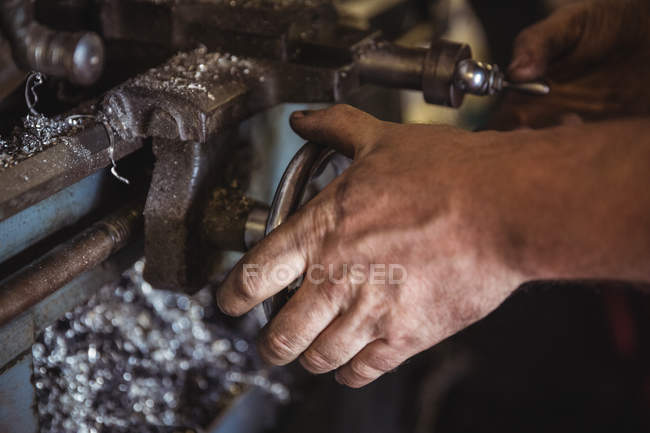 Mécanicien travaillant sur une machine de tour industrielle en atelier — Photo de stock