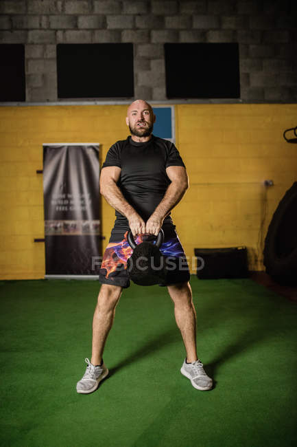 Handsome sportsman lifting weight in gym — Stock Photo
