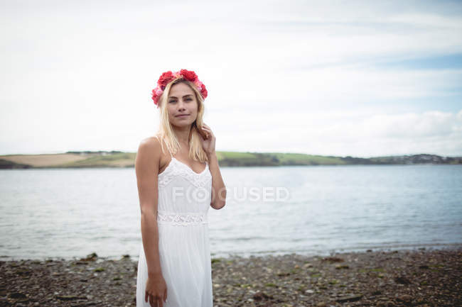 Donna bionda spensierata in abito bianco e fiore tiara in piedi vicino al fiume — Foto stock