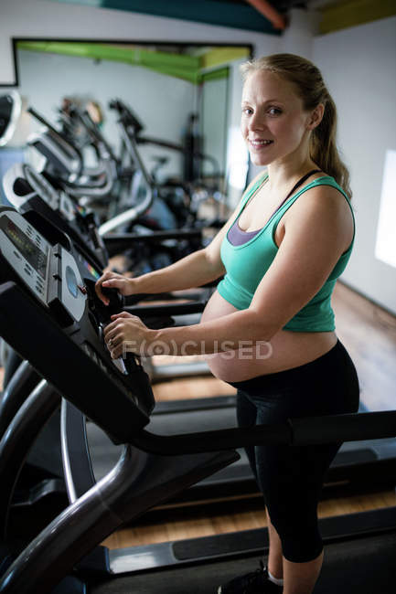 Портрет беременной женщины, занимающейся на беговой дорожке в спортзале — стоковое фото