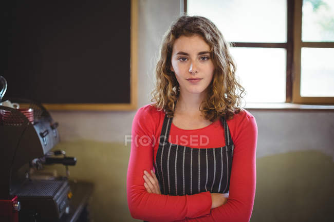 Confident waitress standing with arm crossed in cafe at bicycle shop — Stock Photo