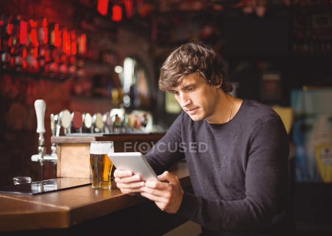 Uomo che utilizza tablet digitale al bancone bar nel bar — Foto stock